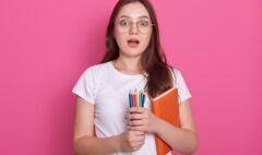 astonished-woman-with-opened-mouth-carries-textbook-colored-pencils-writing-drawing-being-ready-make-notes_176532-9673
